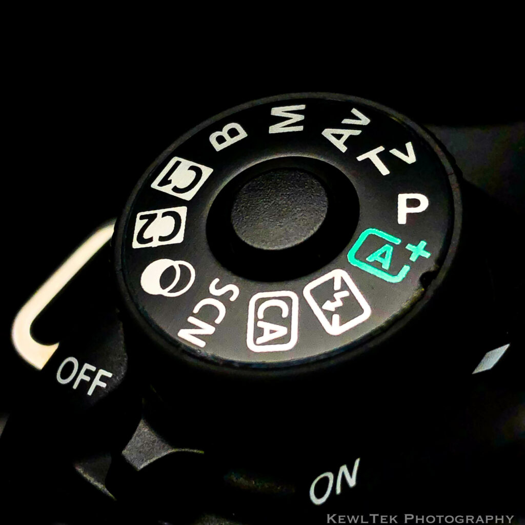 A close up image of a camera's mode dial, depicting Auto Mode, Manual Mode, and other modes.