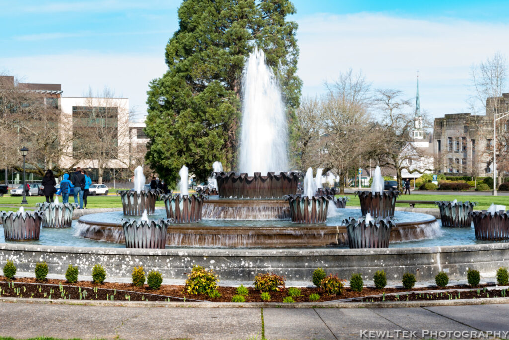 Photograph of a large decorative fountain in a town park with that misty look. 