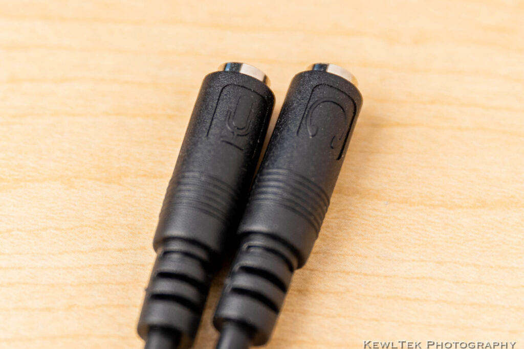 Close up shot of the ends of the StarTech.com Y adapter, showing the embossed icons of a microphone on one tip, and headphones on the other--which is important when you want to connect a Rode VideoMic Go to you laptop--as well as a pair of headphones