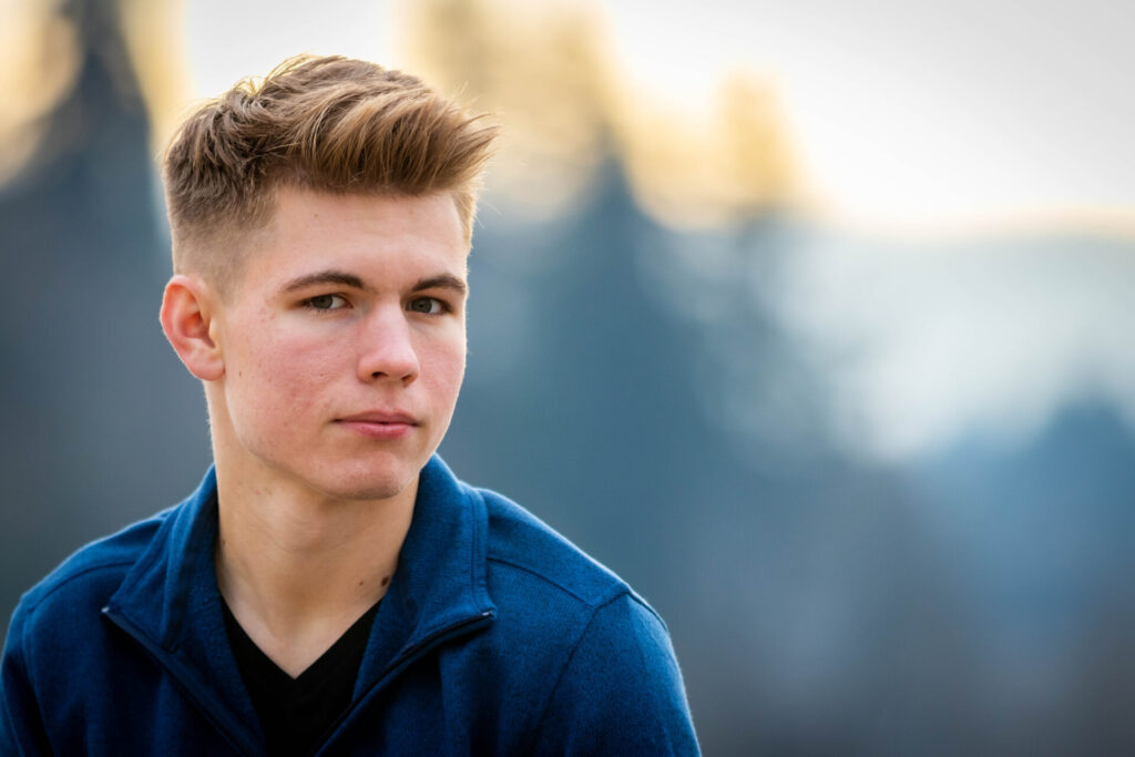 Image of a young man outdoors with lots of empty space behind him, which is blurred into creamy bokeh.