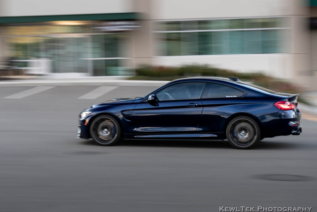 Slow camera shutter speed used to photograph a moving car, resulting in a crisp view of the car with the background is blurred, creating a sense of motion.