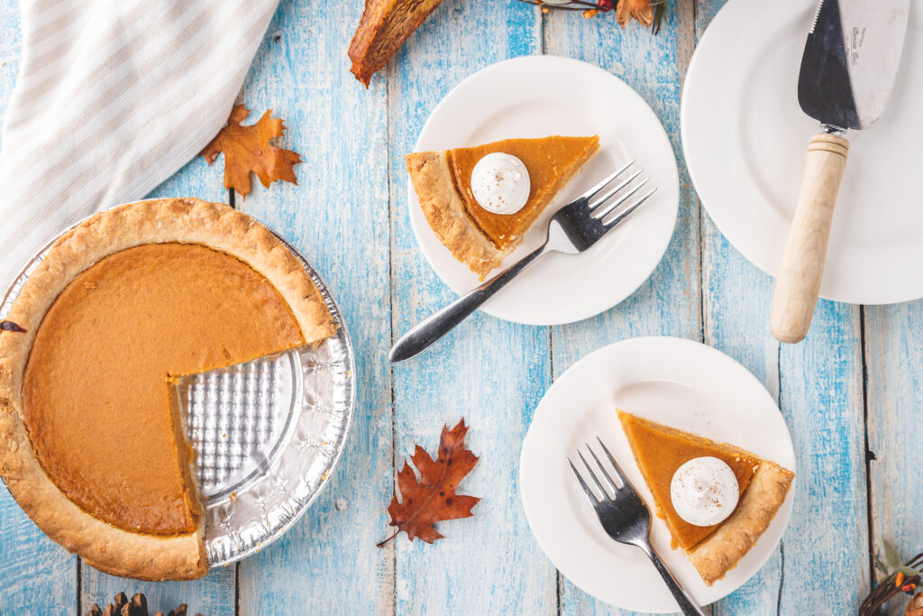 Top down photo of a pumpkin pie and triangular pie slices on circular plates.