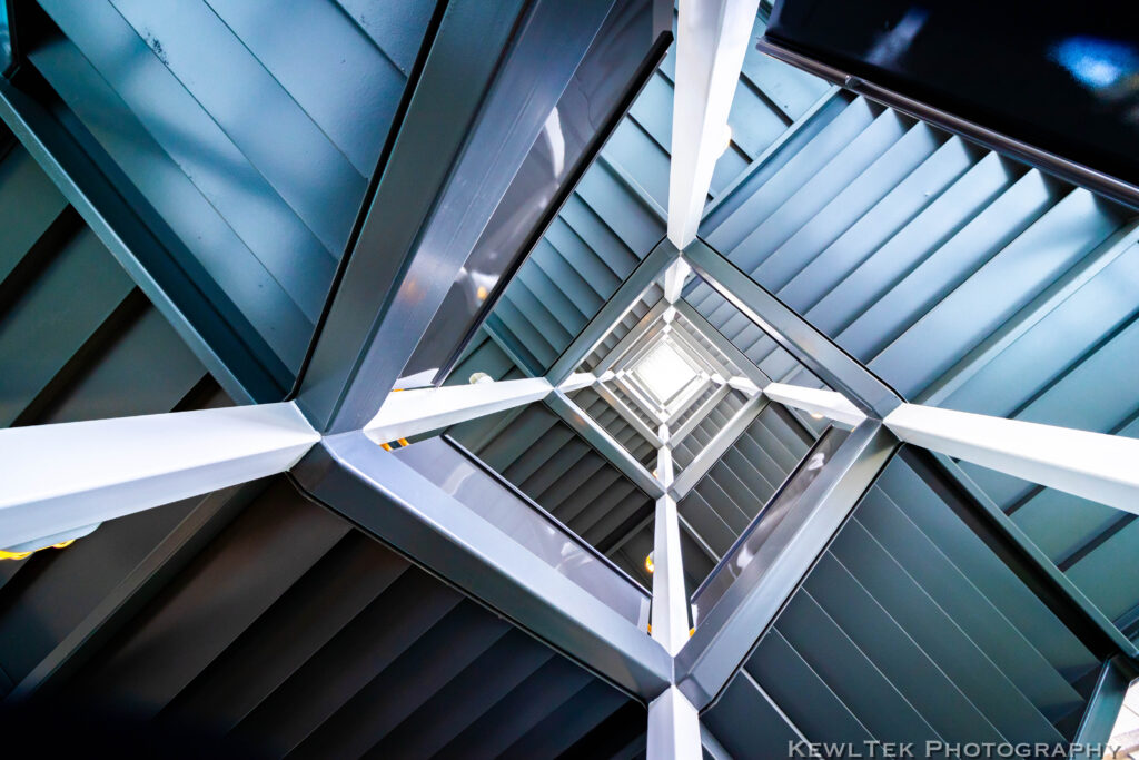 Photo looking upwards into a stairwell, filled with geometric and symmetric shapes.