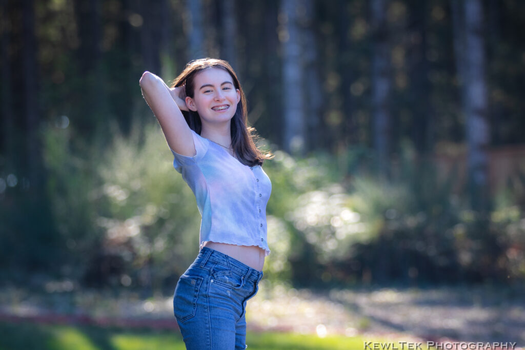 Image of a smiling teenage girl posing in a natural environment for a portrait.