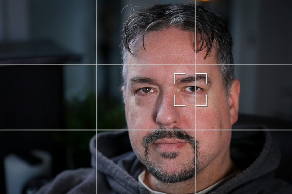 Image of a man seen though "live view" with grid lines, and eye-detect autofocus box over the nearest eye.