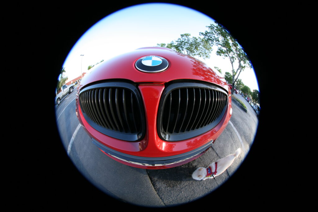 Image of a massively distorted view of the front of a sports car as seen through a circular fisheye lens.
