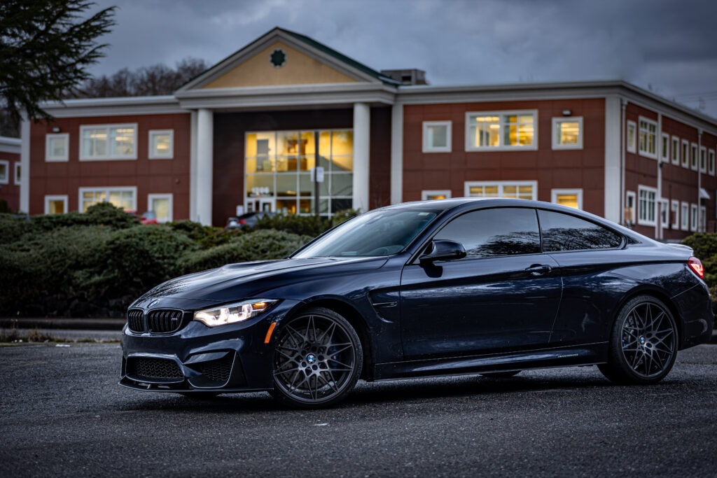 Image of a sports car with an office building in the background at twilight.