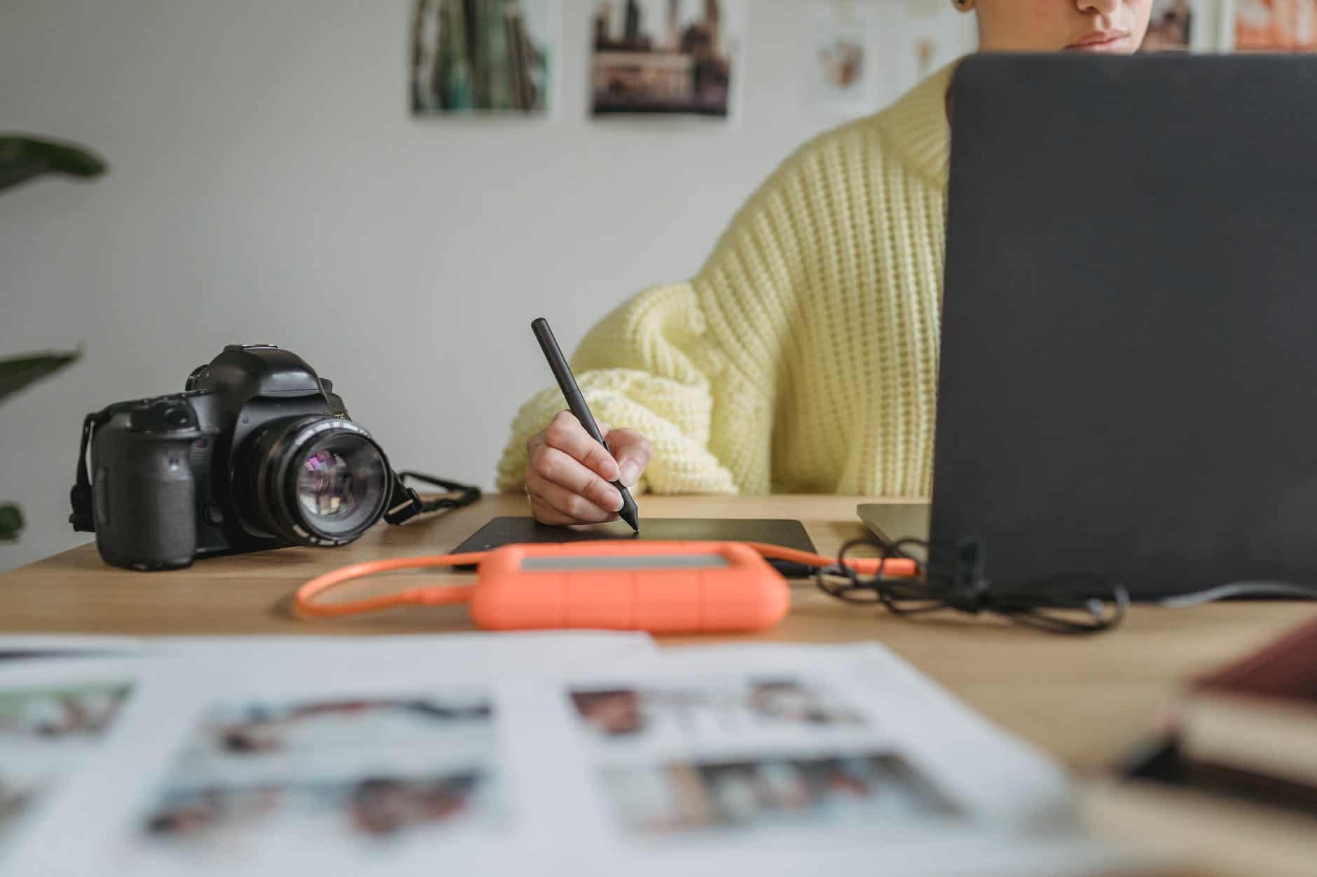 faceless photographer drawing on graphic tablet near laptop