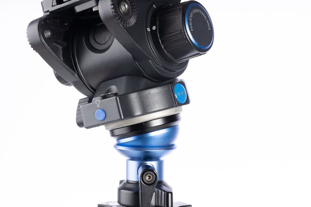 Close-up of a tripod’s half-ball leveling mechanism on the center column, showing the blue leveling adapter and locking knob used for quick horizon adjustments.