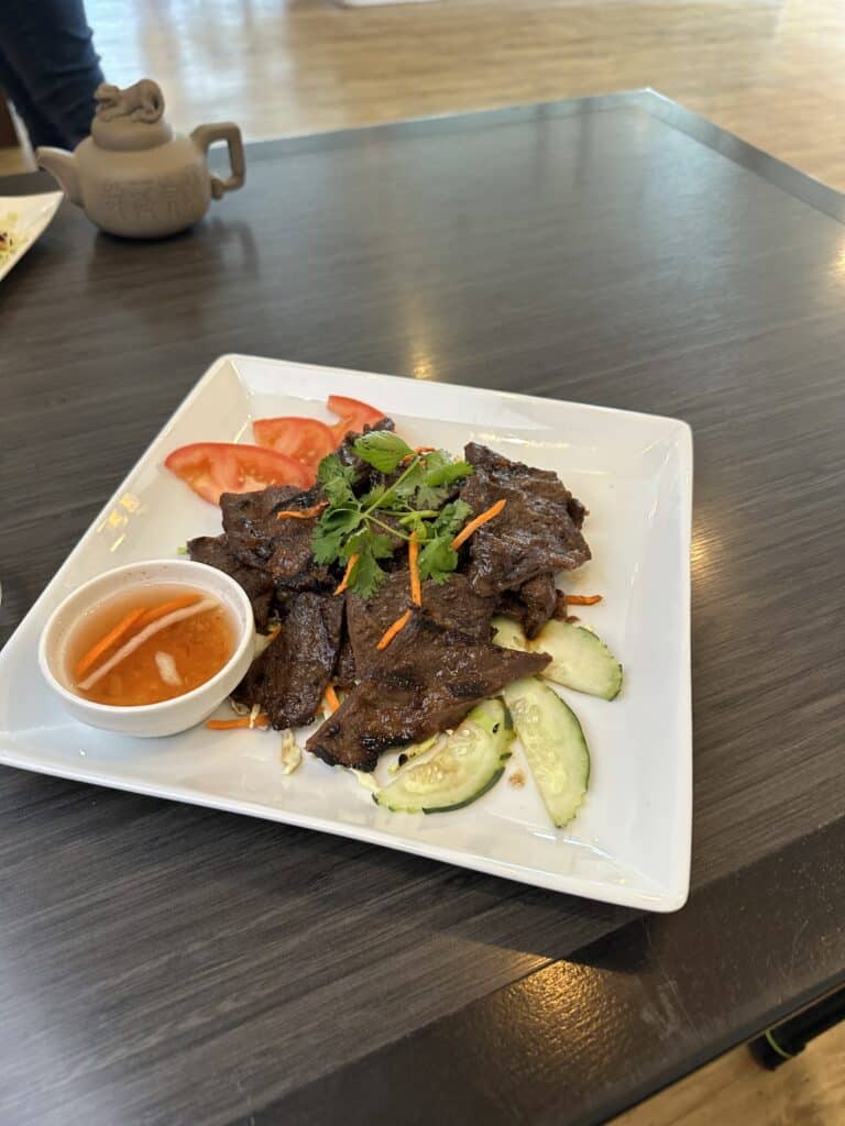beef dish photographed with a smartphone under house lights showing flat dull color and uneven lighting