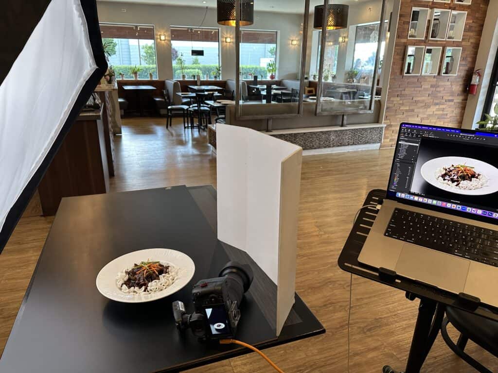 behind the scenes tabletop food photography setup with one softbox light and foam board reflector in a restaurant