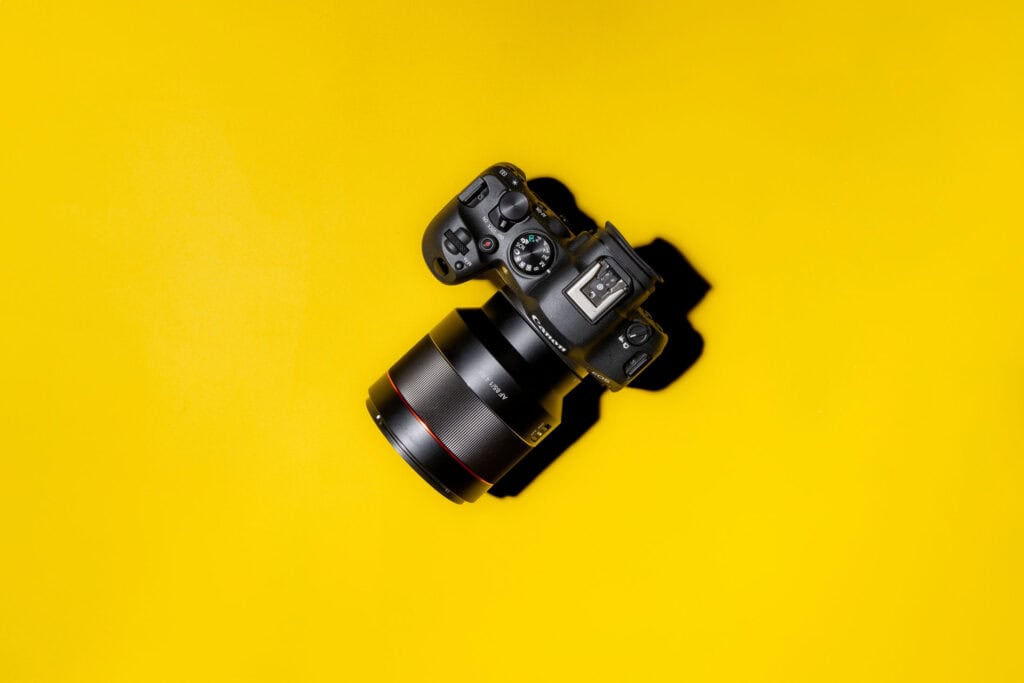 Canon EOS R6 Mark II with a large RF lens placed on a vibrant yellow background, viewed from above.