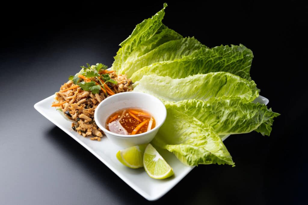 larb salad photographed with artificial lighting showing bright color, clean shadows, on a black surface.