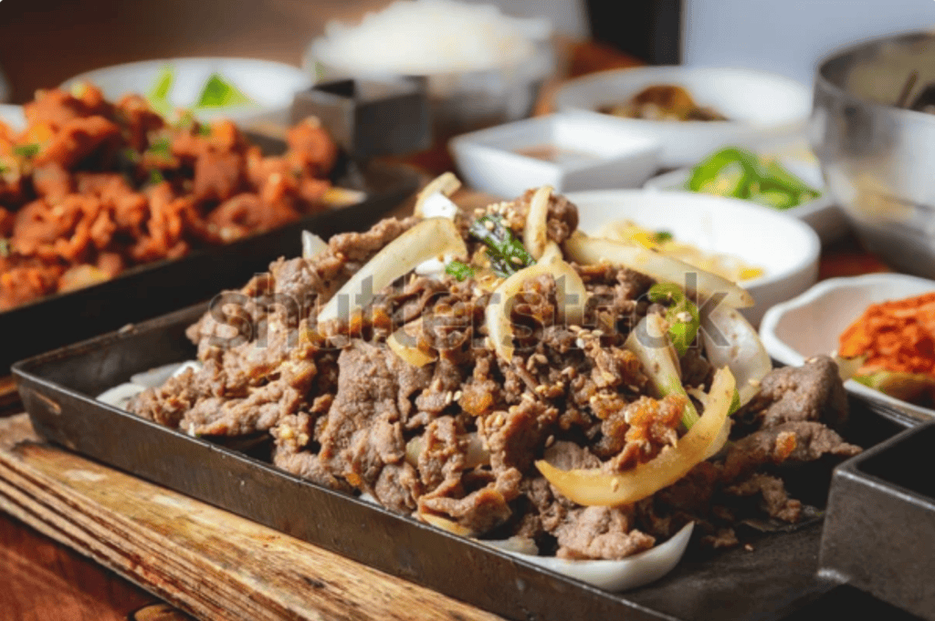 Beef bulgogi served in a cast iron pan with onions and side dishes