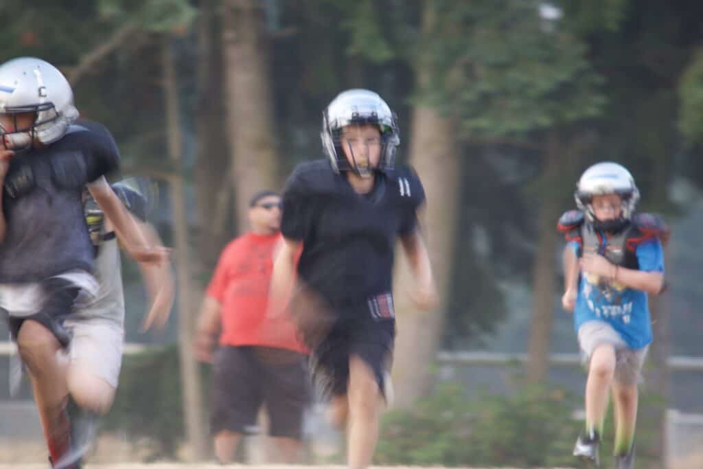 Motion blur from slow shutter speed while photographing running football players with long lens