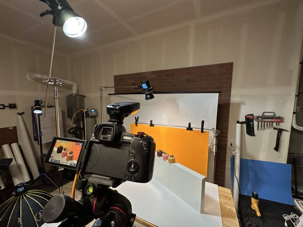 Camera on tripod photographing a tabletop product setup in a small studio